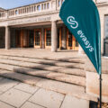 evasys Beachflag vor dem Eingang der Sportwissenschaftlichen Fakultät in Leipzig mit geöffneten Türen bei sonnigem Wetter 