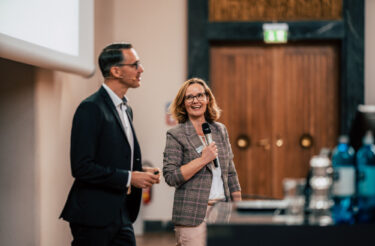 Zwei Personen moderieren gemeinsam auf der Bühne der evasys Tagung