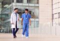 Zwei medizinische Fachkräfte im Gespräch auf dem Flur eines modernen Krankenhauses