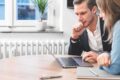 Zwei Personen analysieren gemeinsam Inhalte auf einem Laptop im Rahmen eines Projektmeetings 