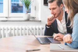 Zwei Personen analysieren gemeinsam Inhalte auf einem Laptop im Rahmen eines Projektmeetings 