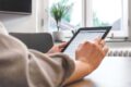 Person füllt eine anonyme Umfrage auf einem Tablet aus, modernes Büro im Hintergrund 
