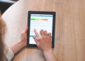 Person bedient ein Tablet mit einer Online-Befragung und Likert-Skala zur Bewertung einer Veranstaltung.