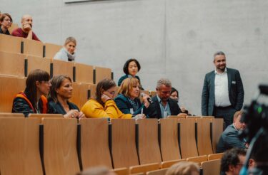 Teilnehmende stellen Fragen während einer Diskussionsrunde im Hörsaal