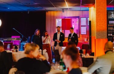 evasys-Team begrüßt die Gäste der Abendveranstaltung auf der Bühne
