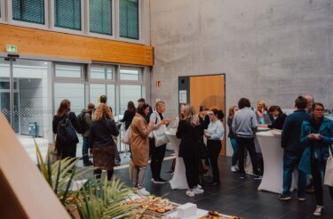Teilnehmende im Foyer der evasys-Tagung 2025 im Gespräch vor Beginn der ersten Keynote