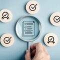 Lupe über einer Checkliste als Symbol für die Prüfung DSGVO-konformer Umfrage-Tools